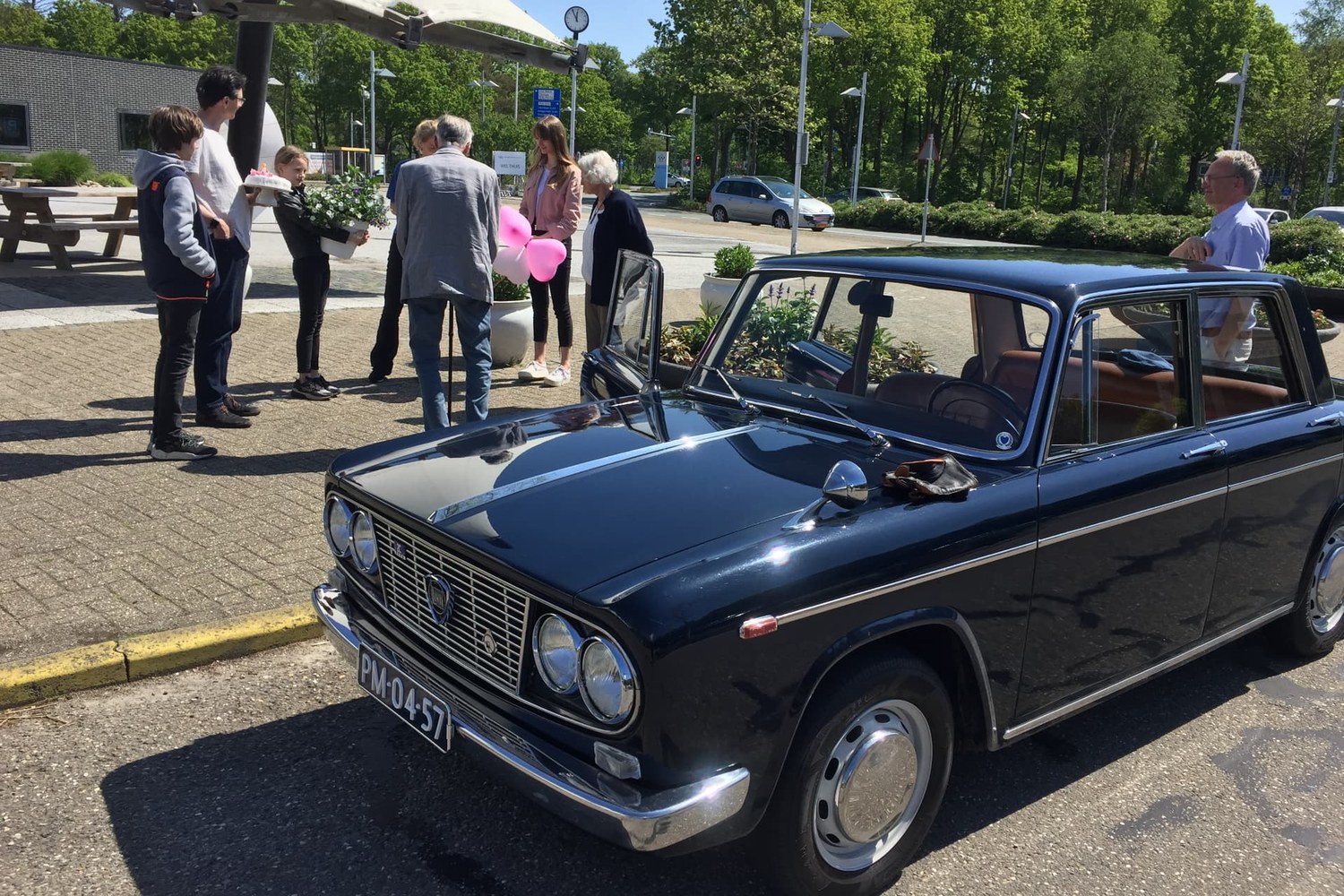 Blauwe Lancia Fulvia bij een feestelijke gelegenheid met gasten